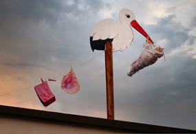 Ein Storch aus Holz hält ein Bündel im Schnabel