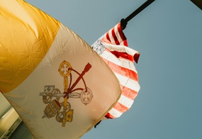 Eine Flagge des Vatikans und der USA wehen im Wind