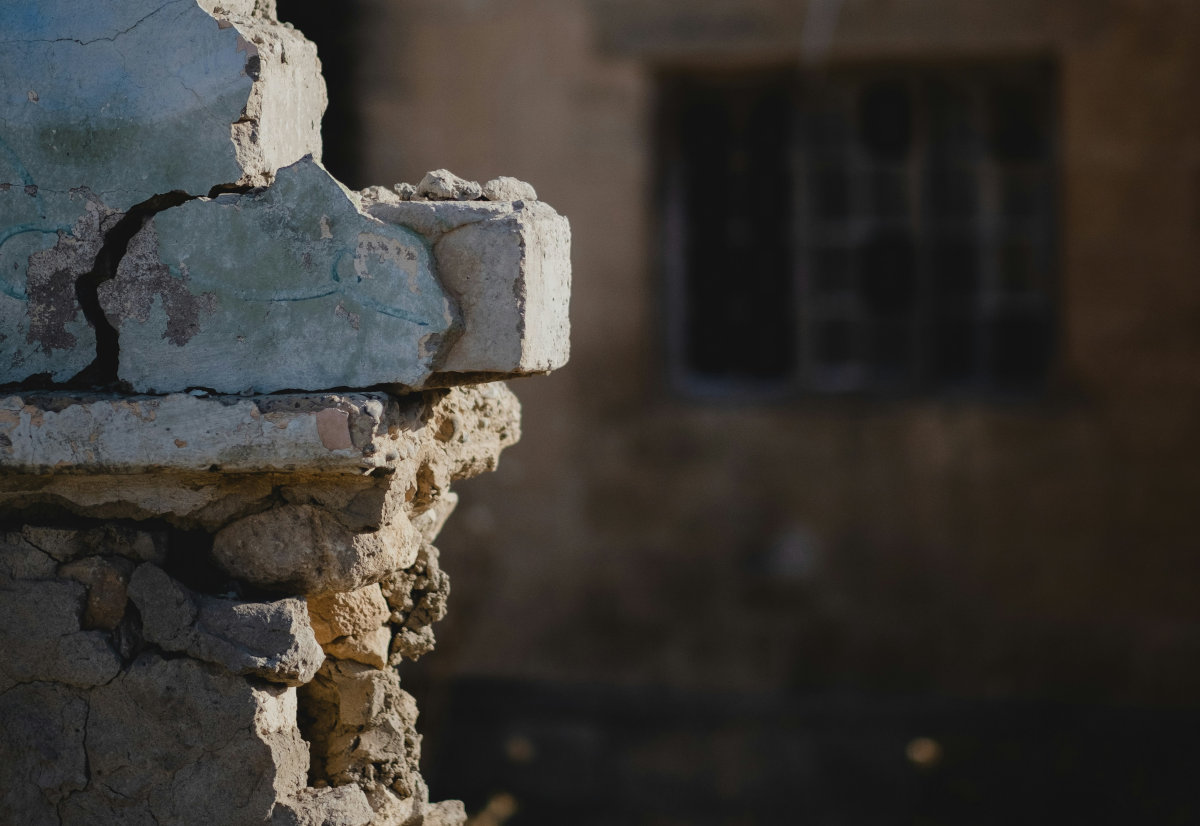 Eine zerstörte Hausmauer ragt aus Trümmern