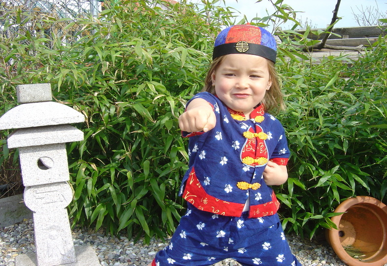 Ein Kind steht breitbeinig da und streckt die rechte Faust nach vorne.