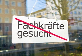 Ein Schild mit der Aufschrift "Fachkräfte gesucht", was durchgestrichen ist.