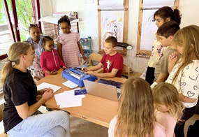 Kinder um einen Schreibtisch