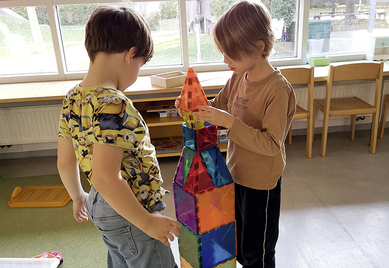 Zwei Kinder baue mit Magnetbausteinen einen hohen Turm.