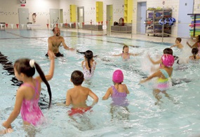 Viele Kinder spielen in einem flachen Wasserbecken.
