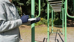 Ein altes Klettergerüst, daneben hält eine Person ein Klemmbrett und notiert etwas.