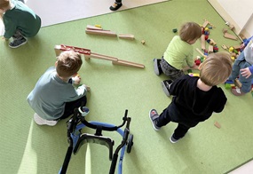 Auf dem Boden spielen Kinder und bauen eine Murmelbahn auf.