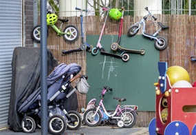 Ein begrenzter Platz, an dessen Wand Roller und Laufräder aufgehängt sind, davor stehen Kinderwagen, Fahrräder und anderes.