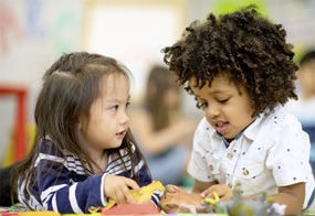 Zwei Kinder spielen gemeinsam mit Tierfiguren.