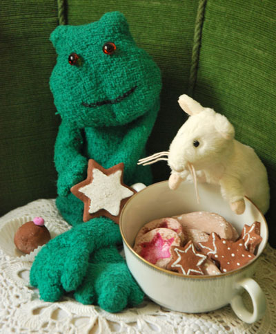 Ein Froschkuscheltier und eine Plüschmaus bewachen eine große Tasse mit Plätzchen.