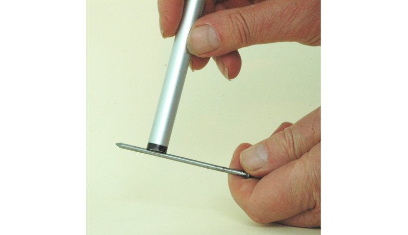 Eine Hand hält einen Nagel, die andere fährt mit einem Stiftmagnet darüber.