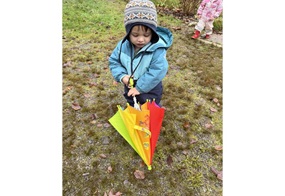 Jakob hat einen bunten Regenschirm in der Hand. 