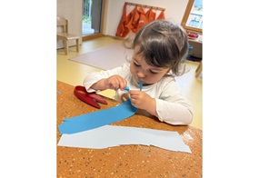 Josi greift nach einem blauen Papierstreifen.