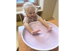 Lotte steht neugierig vor einer Schüssel mit rosafarbener, dickflüssiger Flüssigkeit.