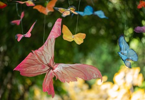 An dünnen Fäden hängen bunte gebastelte Schmetterlinge.