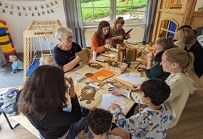 Erwachsene und Kinder sitzen zusammen am Tisch und basteln etwas.