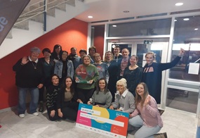 Das Team der Kita Regenbogenland steht zusammen, freut sich, und vor ihnen ist eine große Karte, die zeigt, dass sie einen Preis gewonnen haben.