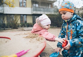 Zwei Kinder spielen im Sandkasten.