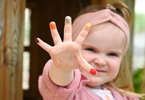 Ein Kind hat Herbstfarben an den Fingerspitzen und hält die Hand direkt ins Bild.