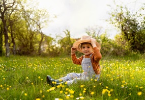 Ein Kind sitzt mitten in einer Blumenwiese.