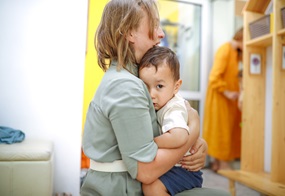 Eine Frau hält ein Kleinkind in den Armen.