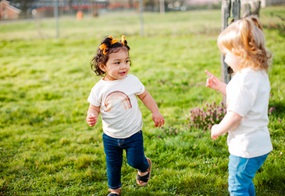Zwei Kleinkinder spielen zusammen auf einer Wiese.