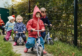 Die Kinder fahren auf ihren Laufrädern gemeinsam in dieselbe Richtung.