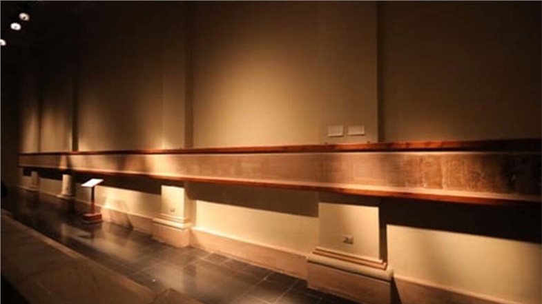 Das Bild zeigt den einen Teil des aufgerollten Papyrus. Dieser ist an einer Wand befestigt.