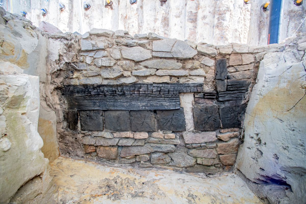 Freigelegtes eisenzeitliches Bauwerk aus Stein und Holzbalken in einer Ausgrabungsstätte