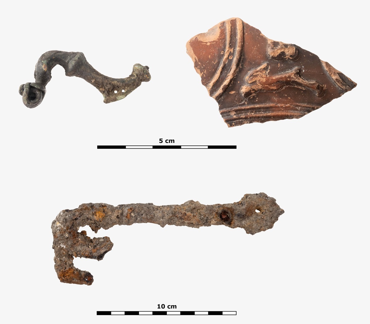 Funde aus der Grabung: Gewandspange (Fibel) aus Bronze, Bruchstück eines Terra Sigillata-Gefäßes mit Darstellung eines Hasen und ein Schlüssel aus Eisen, Römische Kaiserzeit, 1. bis 2. Jahrhundert nach Christus