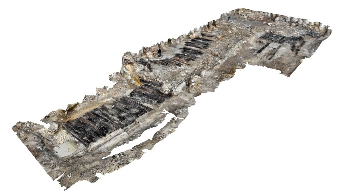 §D Darstellung des archäologischen Fundaments mit rechteckiger Struktur und dunklen Holzresten im Boden