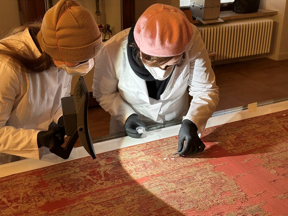 Textilrestauratorinnen markieren Schimmelstellen am Alexandermante