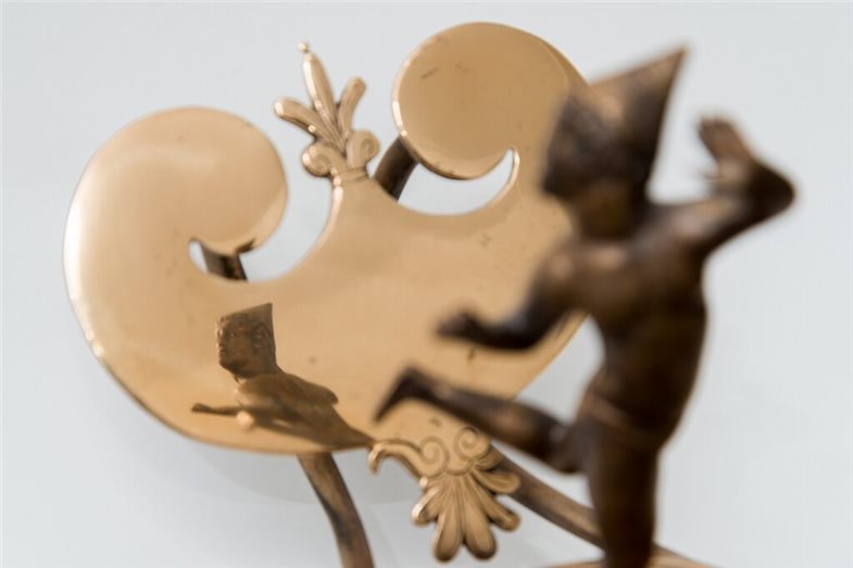 Zu sehen ist eine Lampe mit Tänzerfigur, die sich im polierten Reflektor hinter ihr spiegelt.