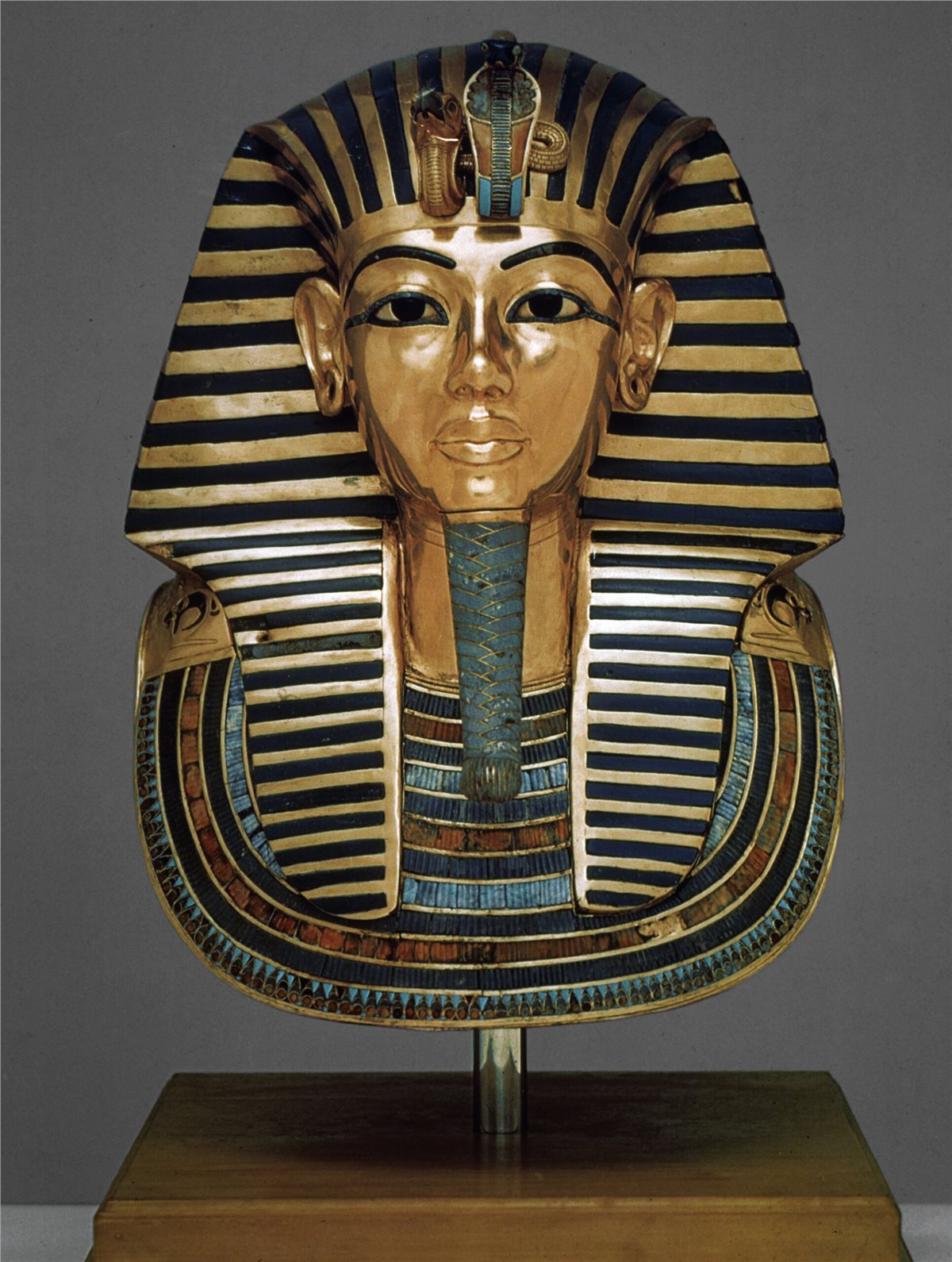 Die goldene Totenmaske des Tutanchamun zeigt das idealisierte Antlitz des jungen Herrschers mit Nemes-Kopftuch und breitem Schmuckkragen. An seiner Stirn sind Geier und Kobra zu sehen, welche Ober- und Unterägypten repräsentieren.