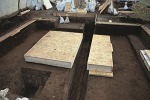 Fundstelle mit den beiden im Block geborgenen Resten der Grabgrube, dazwischen der 55 cm breite Leitungsgraben, der 1934 zur Entdeckung führte.