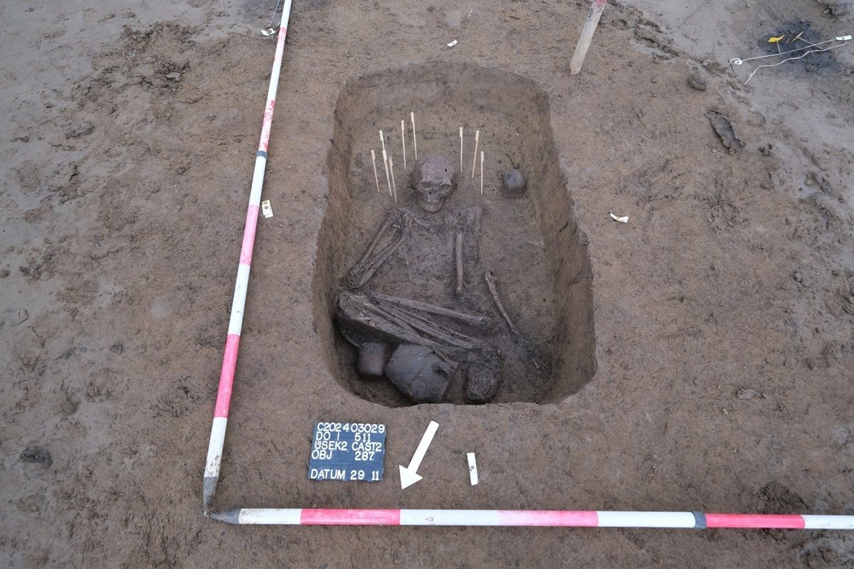 Reich ausgestattetes Grab einer Frau der Glockenbecherperiode, die neben fünf Keramikgefäßen (eines ist unter ihren Füßen verborgen) kleinen Knochenschmuck um ihren Kopf verteilt hatte.