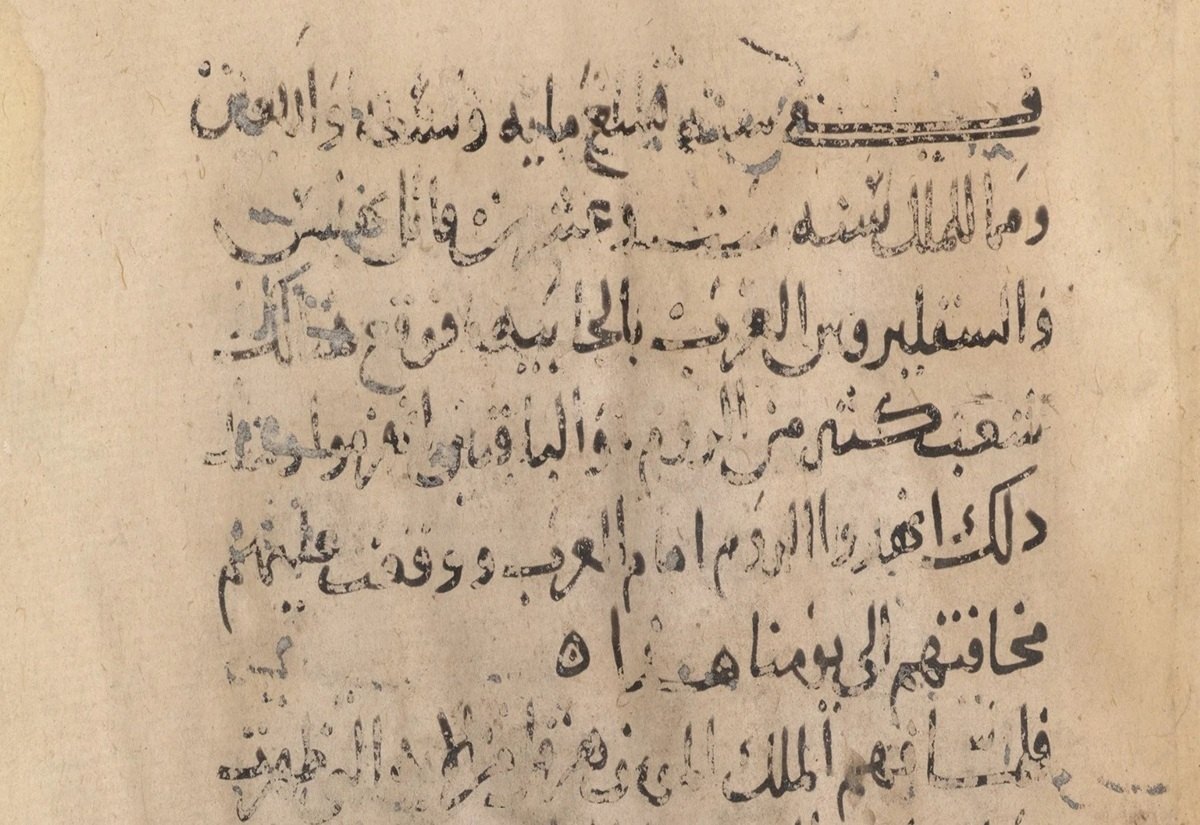 Handschriftliche arabische Schriftzeichen auf vergilbtem, fleckigem Papier. Die Zeilen verlaufen horizontal und sind teilweise verblasst oder durch Tintenflecken unterbrochen. Die Buchstaben sind klar voneinander abgegrenzt und in dunkler Tinte ausgeführt. Es sind keine Illustrationen oder grafischen Elemente zu erkennen.
