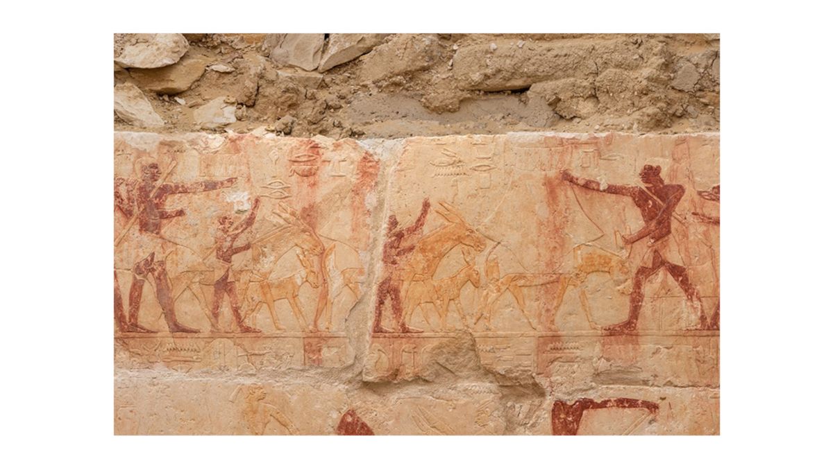 Wandrelief mit mehreren menschlichen Figuren und Tieren in altägyptischem Stil auf einer Steinmauer
