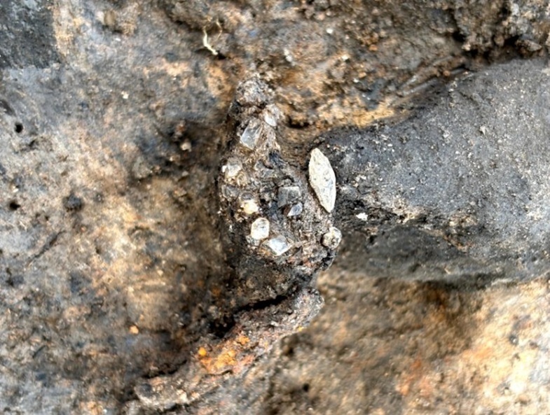 Nahaufnahme des Ausgrabungsbereichs mit kleinen Kristallen und Steinen in der Oberfläche.