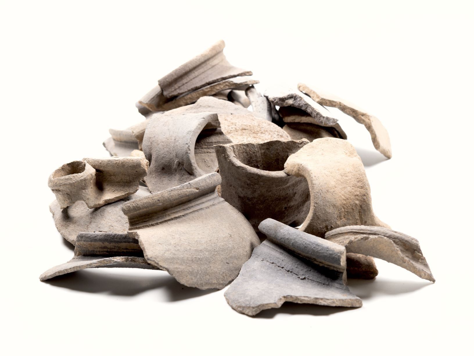 Mehrere Bruchstücke von mittelalterlicher Keramik, unterschiedlich geformt und in Grautönen, liegen aufeinander gestapelt.