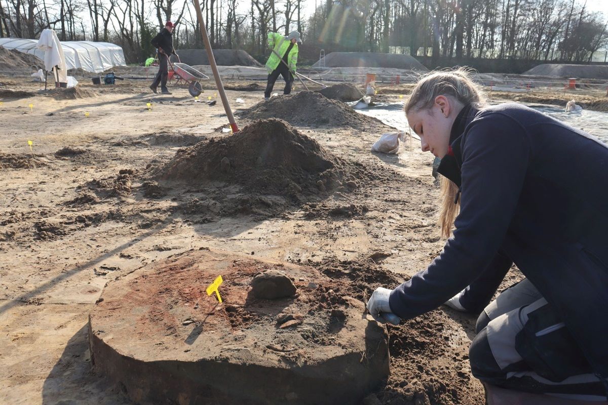 Eine Herdstelle in Form eines dicken, verziegelten Lehmpakets wird vorsichtig freigelegt.