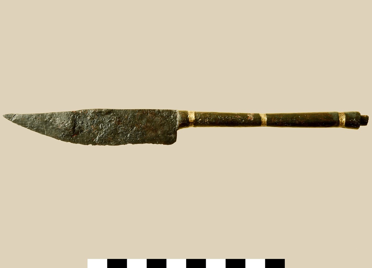 Ein knapp 20 cm langes Messer mit eingelegten Messingstreifen war unter dem Fußboden eines kleinen Nebengebäudes vergraben. Grabung Delbrück-Bentfeld