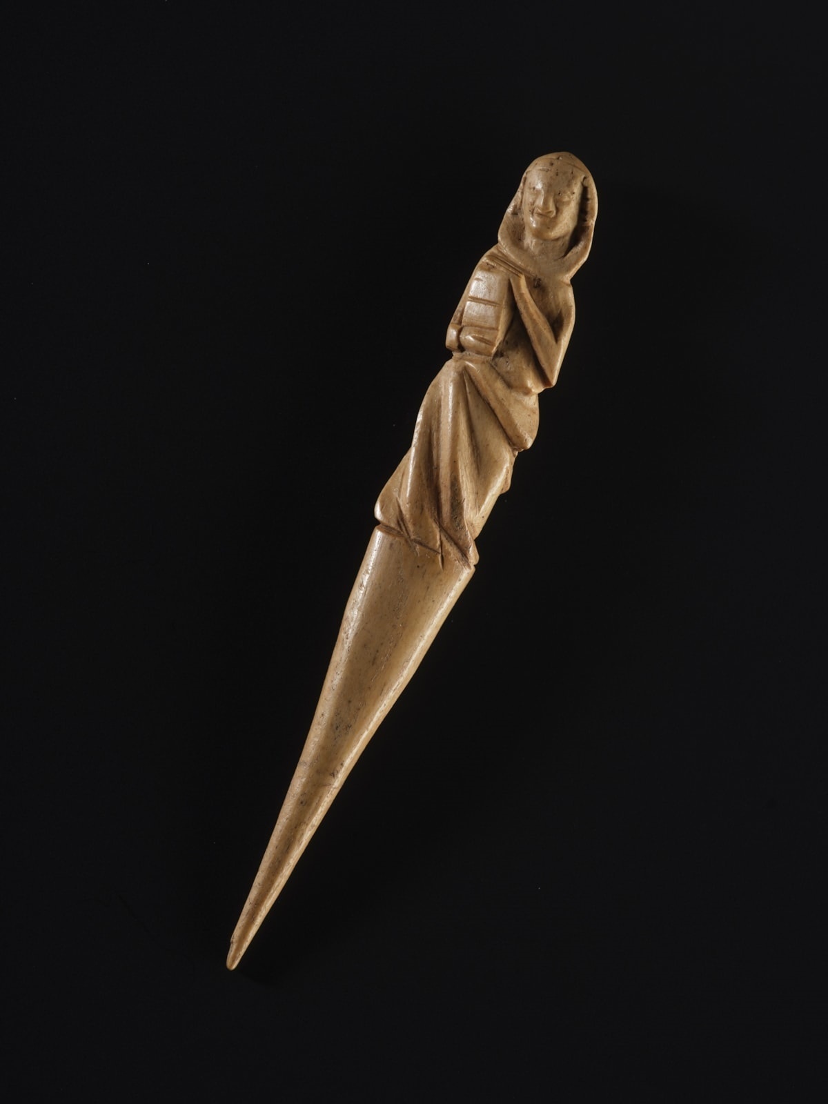 Geschnitzte Figur einer  Frau mit langem Kleid, die ein Buch hält, auf spitz zulaufendem Stab