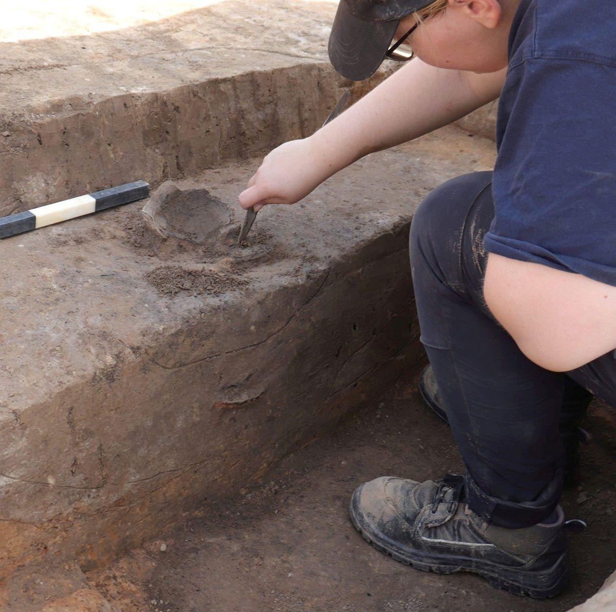 Archäologe untersucht mit Werkzeug eine Ausgrabungsstätte mit Tonfragmenten am Dortmunder Flughafen