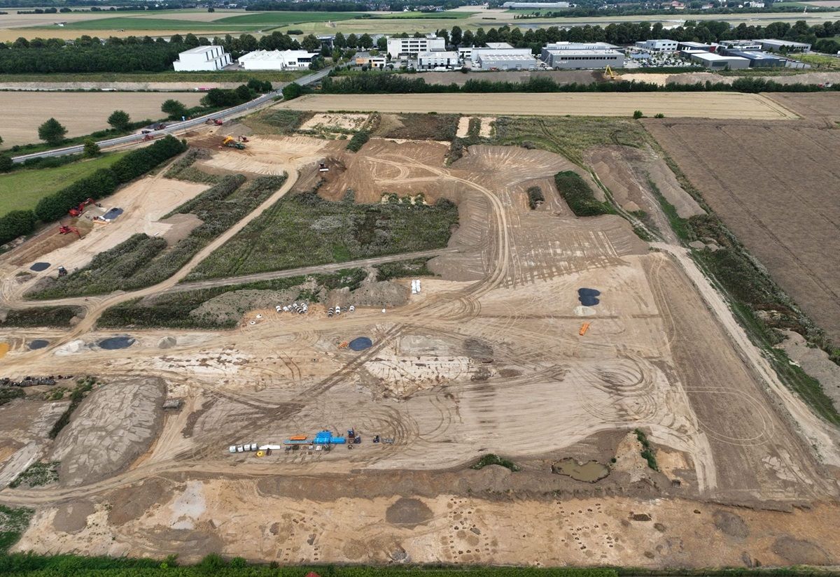 Luftaufnahme einer archäologischen Ausgrabungsstätte mit sichtbaren Grabungsflächen und landwirtschaftlichen Feldern am Dortmunder Flughafen
