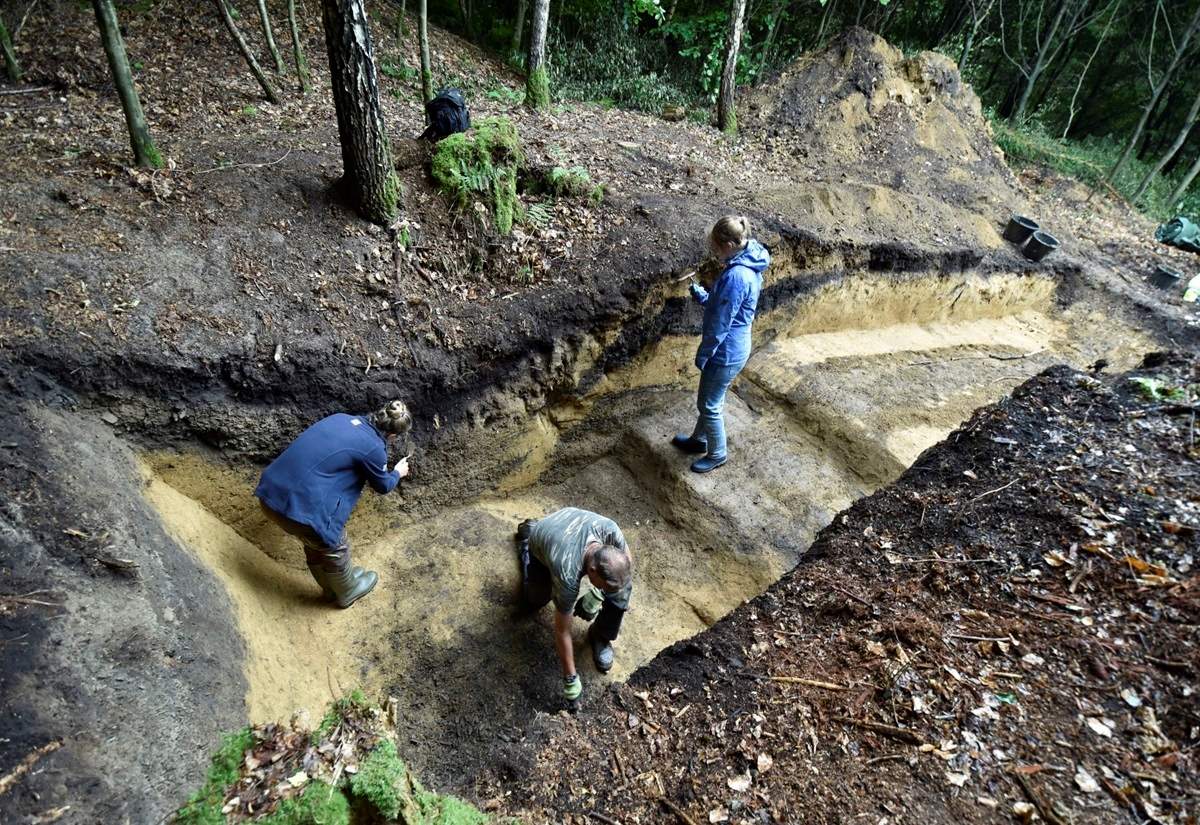 Zwei Archäologinnen und ein Archäologe bei der Arbeit in einem archäologischen Schnitt eines Altbergbaus in einem Wald bei Sprockhövel-Haßlinghausen