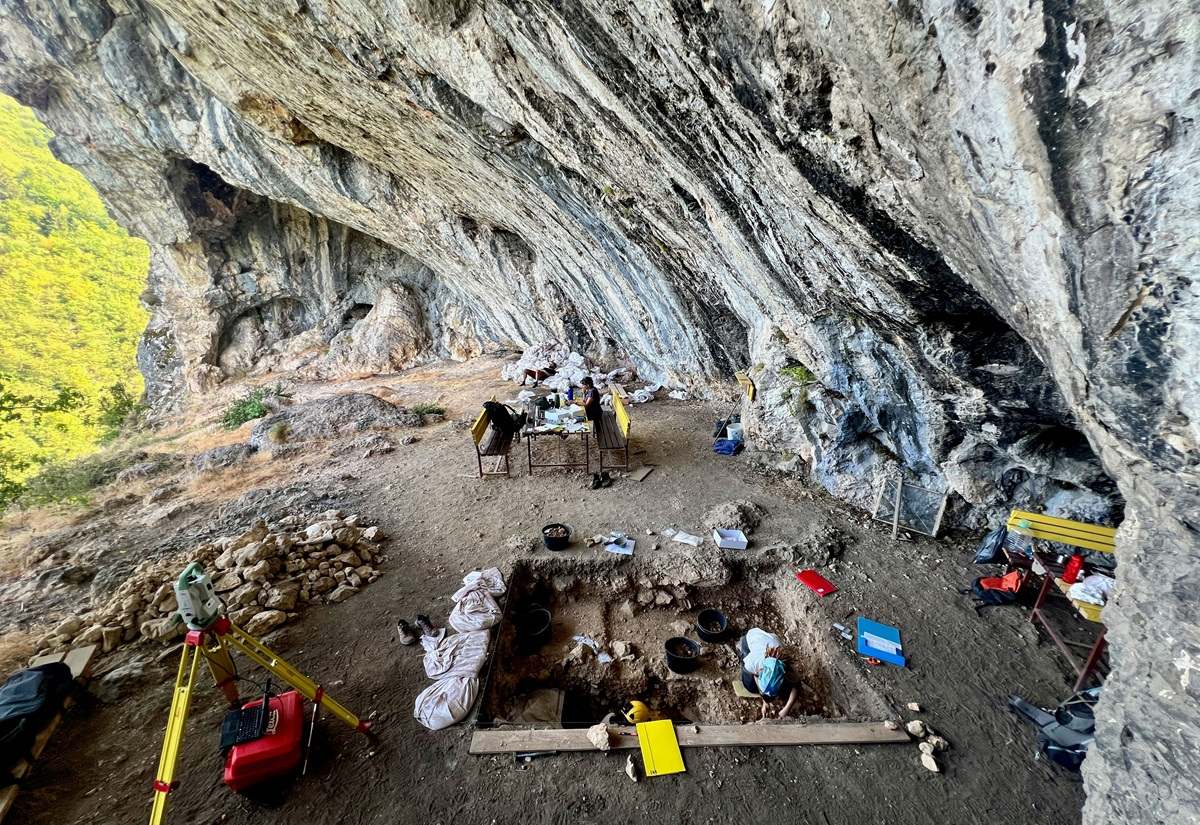 Archäologische Ausgrabungsstätte in einer Felsüberhanghöhle mit mehreren Personen und Ausgrabungswerkzeugen