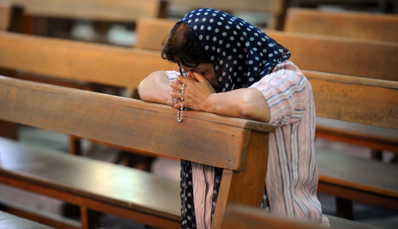 Irakische Christin betet in einer Kirchenbank