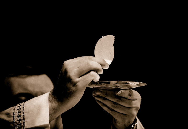 Ein Priester hält das eucharistische Brot