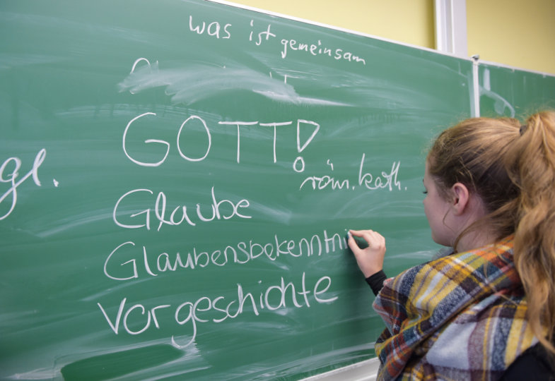 Schülerin schreibt etwas auf eine Tafel