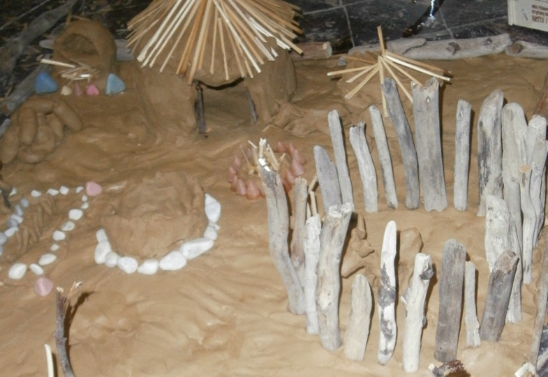 Mit Ton und Knoblauchpresse: Auf einer Arbeitsunterlage aus Massivholz und einer Schicht Ton stehen die Hütte und Eingrenzungen für das afrikanische Dorf stabil.